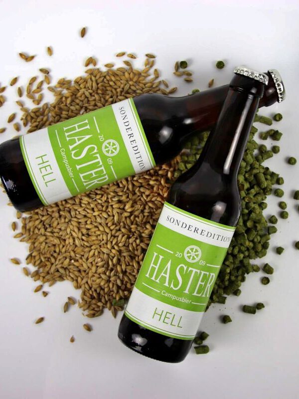 zwei Flaschen Haster hell auf einem kleinen Haufen Gerstenkörner